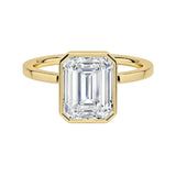 Modern bezel set emerald cut moissanite solitaire ring with a flat gold band ApolloGem