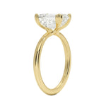 Detailed side view of an emerald moissanite ring showing the double cat-claw prongs and slim polished band.