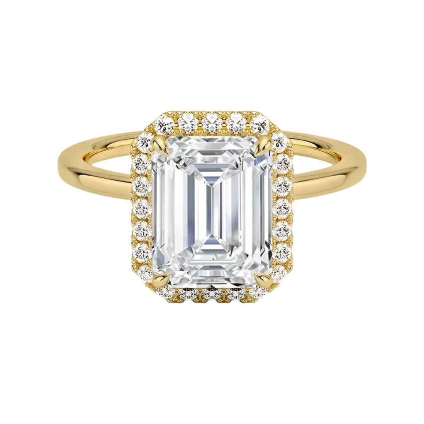 A Halo Emerald Cut Engagement Ring with a large central moissanite stone in an emerald cut setting, surrounded by a halo of smaller moissanite stones set in a gold band.