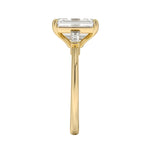 Gold ring with a rectangular diamond on a white background ApolloGem engagement ring emerald cut