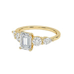 Gold ring with emerald-cut diamond and round diamonds on a white background