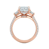 Top-down view of a symmetrical emerald and trapezoid moissanite ring on a luxurious triple-row pavé gold band.