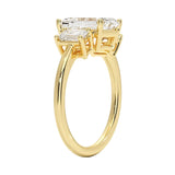 Detailed side view showing the architectural basket settings for the three-stone emerald ring.