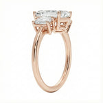 Detailed side view showing the architectural basket settings for the three-stone emerald ring.