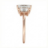 Symmetrical top-down view of a graduated triple emerald-cut moissanite ring in polished solid gold.