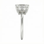 Symmetrical top-down view of a graduated triple emerald-cut moissanite ring in polished solid gold.