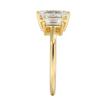 Symmetrical top-down view of a graduated triple emerald-cut moissanite ring in polished solid gold.