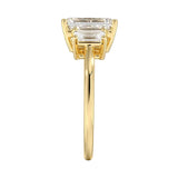 Symmetrical top-down view of a graduated triple emerald-cut moissanite ring in polished solid gold.
