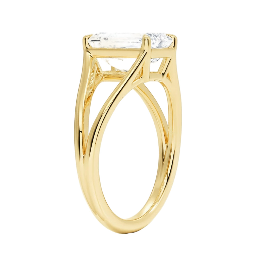 Detailed side view of an emerald moissanite ring showing the architectural V-split shoulder design and four-prong setting.