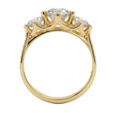 Top-down view of a D-color VVS1 graduated three-stone round moissanite ring with accent stones.