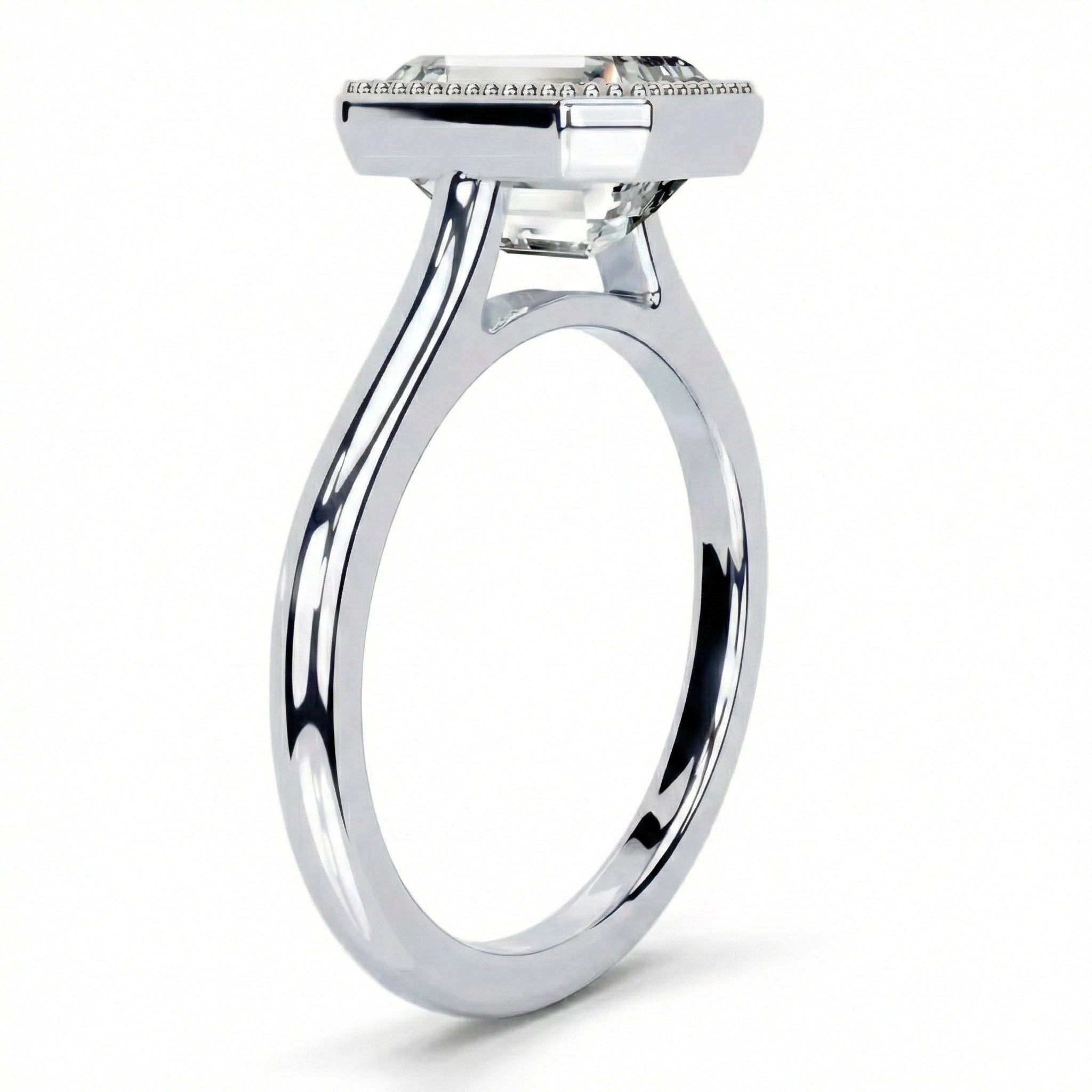 Milgrain detail on gold bezel setting step cut emerald stone close up