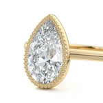 Pear shape Moissanite lab grown diamond engagement ring round shank with a bezel setting, on a gold band, against a white background.Moissanite engagement ring cape town south africa grand diamonds ralph jacobs jeulia 