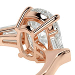 Rose gold ring with a large diamond and smaller baguette-cut diamonds on a white background