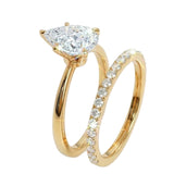 Three-prong pear-cut moissanite solitaire with a shimmering micro-pavé wedding ring in solid gold.