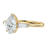 Detailed close-up of a GRI certified D-color VVS1 pear moissanite with crisp tapered baguette side stones in 18k gold.