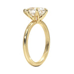 Detailed side view of a pear shaped moissanite ring showing the protective V-prong and slim gold band.