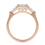 Rose gold ring with a central diamond flanked by two smaller diamonds on a white background