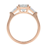 Rose gold ring with a central diamond flanked by two smaller diamonds on a white background
