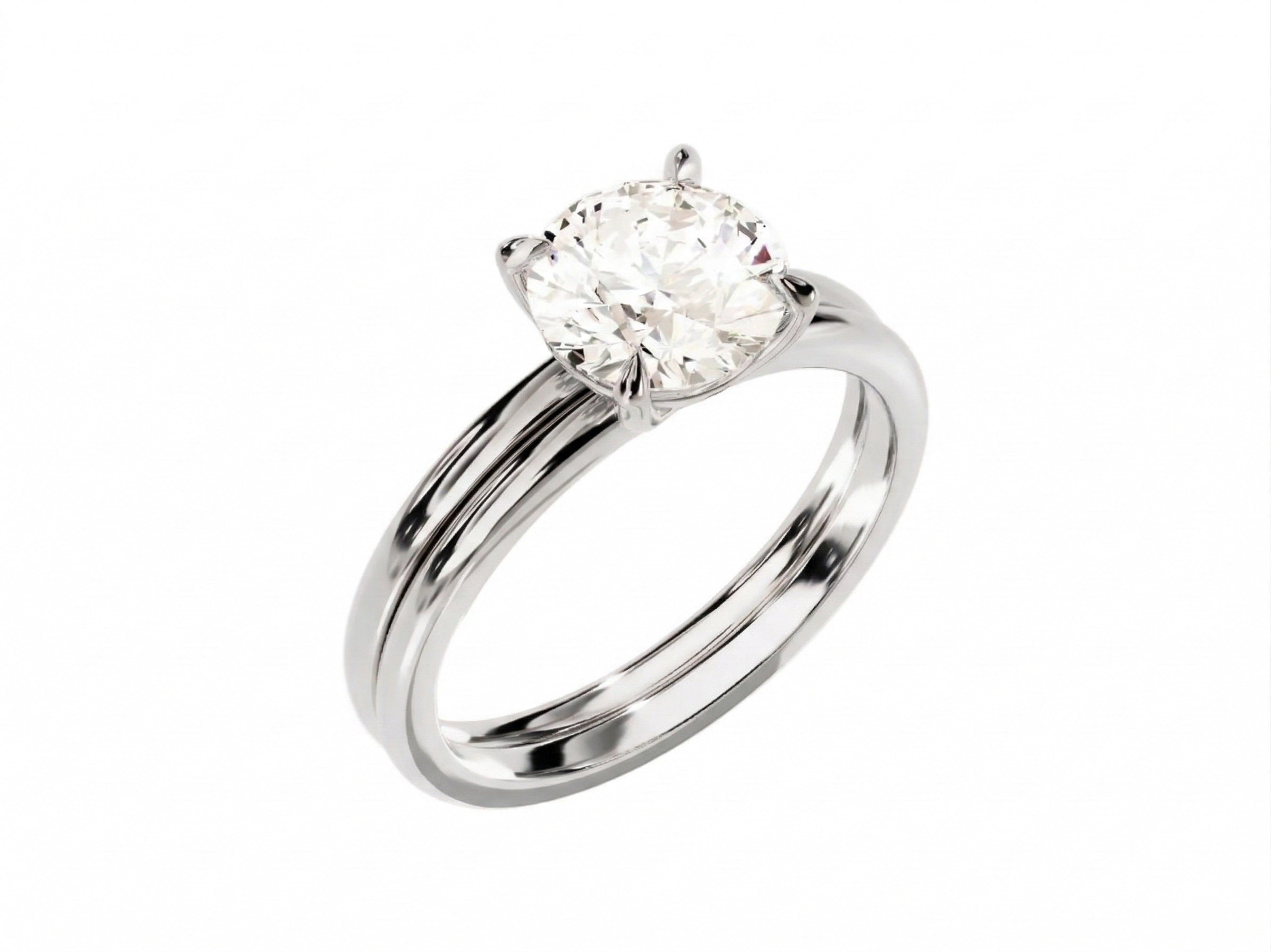 Four-prong round solitaire with a dainty polished shank and matching wedding ring in white gold.