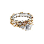 Round moissanite with symmetrical pear accents and a marquise interval wedding band in two-tone gold.