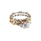 Round moissanite with symmetrical pear accents and a marquise interval wedding band in two-tone gold.