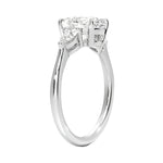 Top-down view of a symmetrical round moissanite ring with two pear side stones on a polished yellow gold comfort-fit shank.