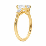 Detailed side view of a round moissanite engagement ring showing the secure four-prong setting and teardrop pear-shaped side stones.