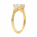 Detailed side view of a round moissanite engagement ring showing the secure four-prong setting and teardrop pear-shaped side stones.