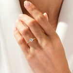 Dainty yellow gold engagement ring with a round brilliant moissanite and pavé band shown on a woman's hand ApolloGem Cape Town.