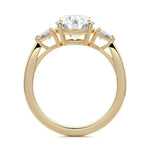 Top-down view of a symmetrical round brilliant ring with trillion accents on a polished 18k yellow gold shank.
