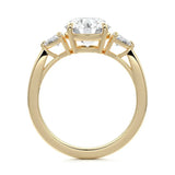 Top-down view of a symmetrical round brilliant ring with trillion accents on a polished 18k yellow gold shank.