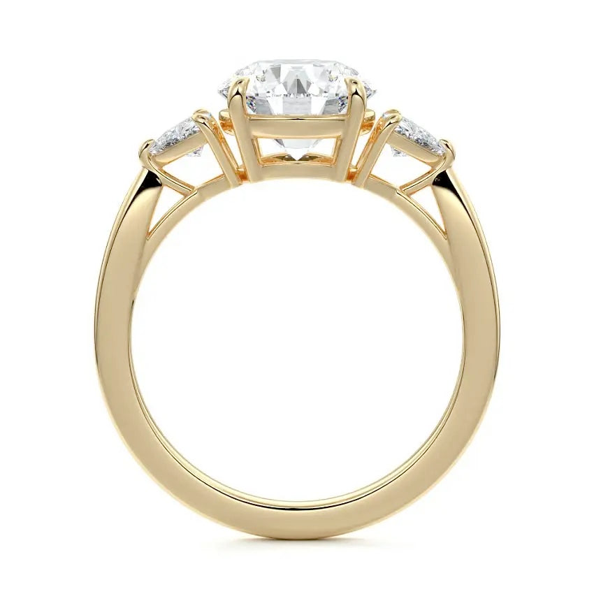 Top-down view of a symmetrical round brilliant ring with trillion accents on a polished 18k yellow gold shank.