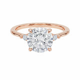 Round brilliant moissanite engagement ring with pear cut side stones rose gold